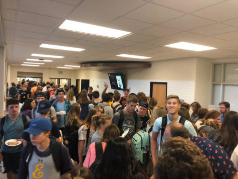 A crowd of students in the hallway next to the cafeteria wait patiently to receive their free food during fourth hour lunch.