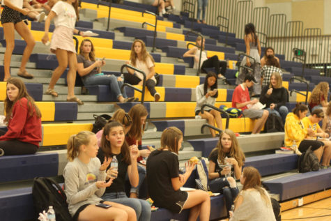 Students eat and converse on the bleachers in the main gym.