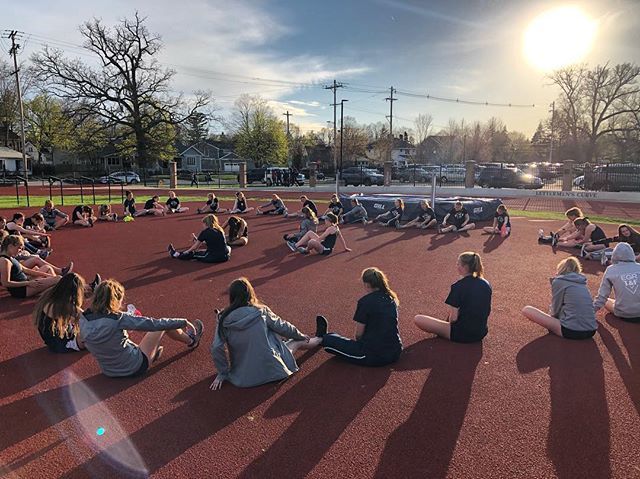 The track and field team gathers together for stretching after practice.